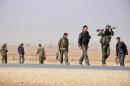 Members of the Kurdish People's Protection Units carry their weapons as they walk in the west of the city of Ras al-Ain
