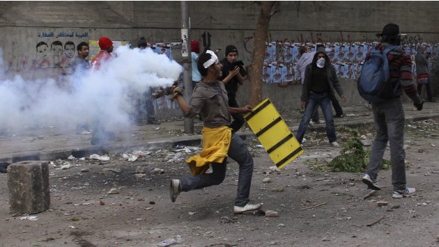 A protester throws a tear gas canister, which had earlier been thrown by riot police, near Tahrir Square