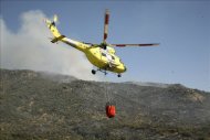 Un helicóptero llevando agua para arrojar sobre el incendio desatado la semana pasada en la sierra de San Vicente, en Toledo. EFE/Archivo