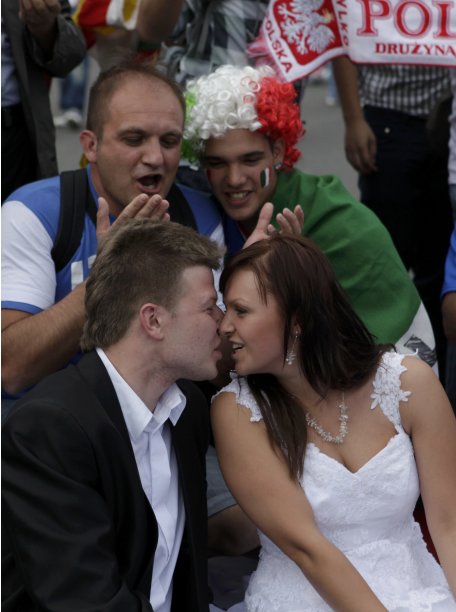 Polish newly-weds kiss as they sit on an Italian national flag in front of the National stadium in Warsaw