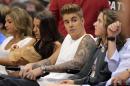 FILE - This May 11, 2014 file photo shows singer Justin Bieber, second from right, watching the Los Angeles Clippers play the Oklahoma City Thunder with his mother Pattie Mallette, second from left, in the first half of Game 4 of the Western Conference semifinal NBA basketball playoff series in Los Angeles. Photographer Aja Oxman sued Bieber and his bodyguard Dwayne Patterson for assault and intentional infliction of emotion distress in Los Angeles on Wednesday, Aug. 20, over an altercation last year on Hawaii's Shipwreck Beach. The lawsuit states Patterson injured Oxman while trying to forcibly retrieve a camera memory card after Bieber spotted the photographer snapping photographs of him leaping off a cliff into the ocean. (AP Photo/Mark J. Terrill, File)