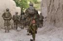 A boy plays on a street as U.S. Army soldiers of 82nd Airborne Division, patrol during a mission in Zahri district of Kandahar province