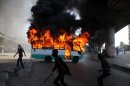 Egyptian protesters clash near a bus belonging to Muslim Brotherhood supporters burns after it was reportedly set alight by anti- government protesters in Cairo, Egypt, Friday, April 19, 2013. Clashes erupted Friday between several hundred opponents and supporters of Egypt's Islamist president during a rally by his allies calling on him to 