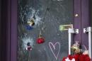 Flowers are seen in the holes from bullet impacts on the door of the"Casa Nostra" pizzeria in Paris
