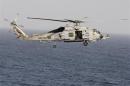 A Sikorsky SH-60 Seahawk helicopter flies near the Nimitz-class aircraft carrier USS Abraham Lincoln (CVN 72) during a transit through the Strait of Hormuz