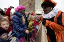 Children, some with faces painted black, wait for "Zwarte Piet" or "Black Pete", right, to hand them candy after they arrived with Sinterklaas, or Saint Nicholas, in Hoorn, north-western Netherlands, Saturday Nov. 16, 2013. The tradition of Sinterklaas, the Dutch version of Santa Claus, is the subject of debate, where opponents say Black Petes are an offensive caricature of black people while supporters say Pete is a figure of fun whose appearance is harmless, his face soot-stained from going down chimneys to deliver present for the children. (AP Photo/Peter Dejong)