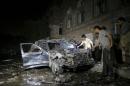 People check a car damaged by a car bomb attack near a mosque in Yemen's capital Sanaa