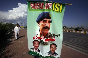 A man walks past a banner showing a picture of Pakistan's …