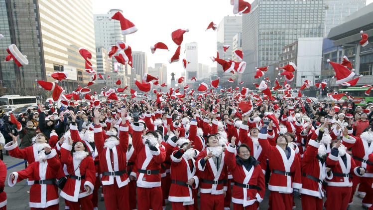More than 1,000 volunteers clad in Santa Claus costumes throw their hats in the air as they gather to deliver gifts for the poor in downtown Seoul, South Korea, Tuesday, Dec. 24, 2013. (AP Photo/Lee Jin-man)