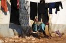 An internally displaced Syrian woman washes clothes inside her tent at the Bab Al-Salam refugee camp, near the Syrian-Turkish border