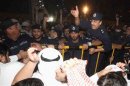 A policeman gestures at Kuwaiti demonstrators during an anti-government protest in front of the parliament in Kuwait City