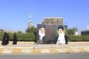 Iraqi women walk towards a poster depicting images of Shi'ite Iran's Supreme Leader Ayatollah Ali Khamenei at al-Firdous Square in Baghdad