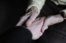 Una mujer con mal de Alzheimer toma la mano de un familiar en la residencia donde vive en Angervilliers, este de Francia