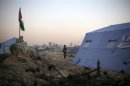 A boy stands near a Palestinian flag placed near newly-erected tents between Ramallah and Jerusalem