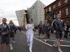 Karen Marshall, the first torch bearer from Northern Ireland, carries the Olympic torch to start the relay from Titanic Museum, background center, in Belfast, Northern Ireland, Sunday, June 3, 2012. (AP Photo/Peter Morrison)
