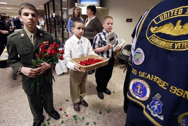 Josh Royer, 14, of Stratham, N.H., left, Alex Cardona, 11, of York, Maine, center, and Alex Coulombe, 11, of Freemont, N.H., offer roses and programs before a service marking the 50th anniversary of the sinking of the USS Thresher, Saturday, April 6, 2013, at the high school in Portsmouth, N.H. (AP Photo/Michael Dwyer)