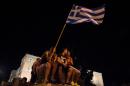 A teen holds a Greek national flag as people celebrate in front of the parliament on July 5, 2015 in Athens