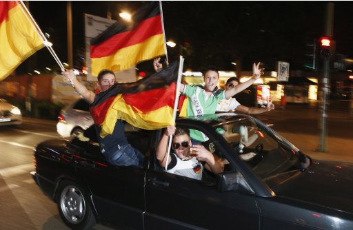 Soccer fans wave German national flags as they celebrate after Euro 2012 Group B match between Germany and Portugal in Berlin
