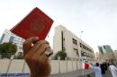 File picture shows an anti-government protester holding up a passport as he protests against nationalisation, in front of the Bahrain Immigration Directorate in Manama