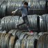 A labourer walks on coils of steel wire at a steel market in Shenyang