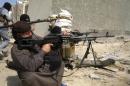 Masked Sunni Muslims gunmen take up position with their weapons during a patrol in Falluja