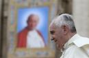 Pope Francis passes next to a tapestry of the late Pope John Paul II, as he leaves at the end of his weekly general audience at St. Peter's Square