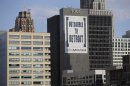 In this July 12, 2013, photo an Outsource to Detroit banner from Galaxe.Solutions is seen on a Detroit building. State-appointed emergency manager Kevyn Orr on Thursday, July 18, 2013, asked a federal judge permission to place Detroit into Chapter 9 bankruptcy protection.. (AP Photo/Carlos Osorio)