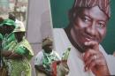 A woman sits beside an electoral poster of Nigeria's President Goodluck Jonathan during the flag-off for his campaign for a second term in office, in Lagos