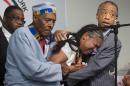 Esaw Garner, center, wife of Eric Garner, breaks down in the arms of Rev. Herbert Daughtry and Rev. Al Sharpton, right, during a rally at the National Action Network headquarters for Eric Garner, Saturday, July 19, 2014, in New York. Garner, 43, died Thursday, during an arrest in Staten Island, when a plain-clothes police officer placed him in what appeared be a chokehold while several others brought him to the ground and struggled to place him in handcuffs. (AP Photo/John Minchillo)