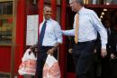 U.S. President Barack Obama walks out with two bags of cheesecake from Junior's Restaurant next to Democratic Mayoral candidate Bill de Blasio in Brooklyn