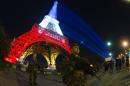 French soldiers patrol on November 18, 2015 in Paris in front of the Eiffel Tower, which is illuminated with the national colourin tribute to the victims of the November 13 terror attacks