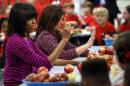FILE - This Feb. 27, 2013 file photo shows first lady Michelle Obama and Food Network chef Rachel Ray discussing lunches with students from the Eastside and Northside Elementary Schools in Clinton, Miss. Moving beyond the lunch line, new rules expected to be proposed by the White House and the Agriculture Department Tuesday, Feb. 25, 2014, would limit marketing of unhealthy foods in schools, phasing out the advertising of sugary drinks and junk foods around school campuses and ensuring that other promotions in schools are in line with health standards that apply to school foods. (AP Photo/Rogelio V. Solis, File)