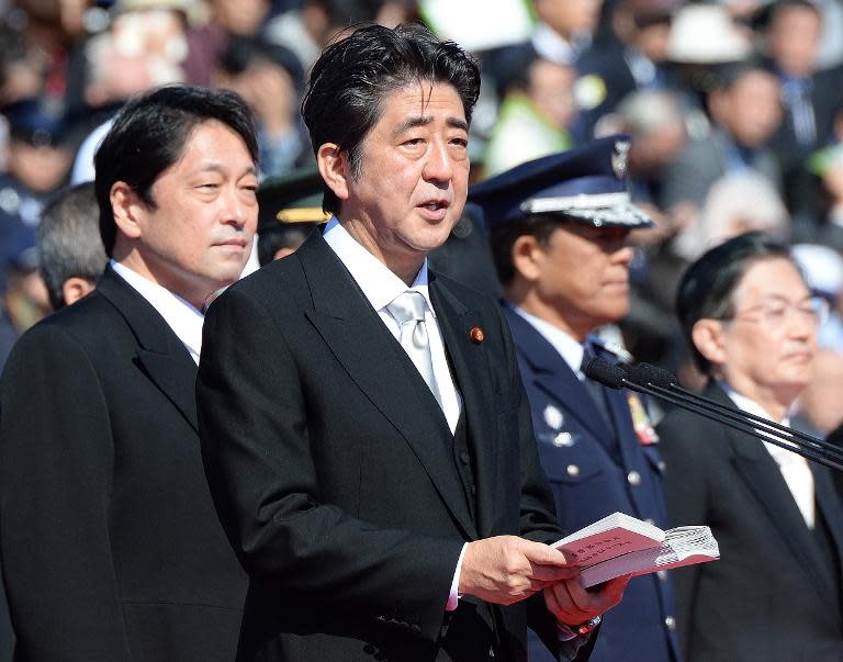 Japanese Prime Minister Shinzo Abe (C) delivers a speech next to Defence Minister Itsunori Onodera (L) during military review at the Ground Self-Defence Force's Asaka training ground, on October 27, 2013