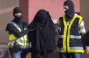 Masked Spanish police officers lead a detained woman in Melilla