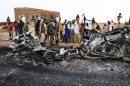 Residents look at the remains of vehicles which they said belonged to radical Islamist group MUJAO, after they were hit by French air strikes in the town of Gao
