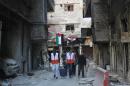 Syrian Red Crescent workers helps residents of the besieged Yarmuk Palestinian refugee camp carry their belongings during an evacuation operation on February 1, 2014