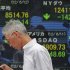 A man uses his mobile phone in front of the electronic stock board of a securities firm in Tokyo, Tuesday, June 12, 2012. Asian stock markets slid Tuesday as enthusiasm for a European plan to rescue Spain's teetering banks turned to skepticism. Japan's Nikkei 225 index fell 1.3 percent to 8,514.76. (AP Photo/Itsuo Inouye)