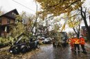 Power workers look at a car that was burned out in an electrical fire after a tree fell over a power line due to the remnants of Hurricane Sandy in Toronto