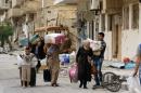 Syrians carry their belongings upon their return to the modern town of Palmyra, adjacent to the ancient Syrian city, on April 9, 2016