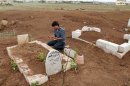 Man prays at the grave of a Free Syrian Army fighter at a cemetery at al-Karak al-Sharqi in Deraa
