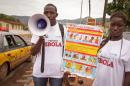 A man and woman taking part in a Ebola prevention campaign holds a placard with an Ebola prevention information message in the city of Freetown, Sierra Leone, Wednesday, Aug. 6, 2014. The World Health Organization has begun an emergency meeting on the Ebola crisis, and said at least 932 deaths in four African countries are blamed on the virus, with many hundreds more being treated in quarantine conditions. (AP Photo/ Michael Duff)