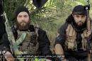 An Austrian Islamic State (IS) group fighter, identified as Mohamed Mahmoud (R) (aka Abu Usama al-Gharib), and his German comrade, named in the video as Abu Omar al-Alamani, speaking in German prior to executing two non-identified men