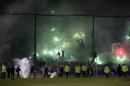 CORRECTS YEAR - Panathinaikos fans light flares as policemen and security personnel enter the pitch after the cancellation of the Greek Super League match between Panathinaikos and Olympiakos at Apostolos Nikolaides stadium in Athens, Saturday, Nov. 21, 2015. The derby between host Panathinaikos and archrival Olympiakos, the Greek league's frontrunner, has been cancelled after Panathinaikos fans clashed with police both outside and inside the football ground before the game and also threw flares at Olympiakos players when the latter entered the field. (AP Photo/Yorgos Karahalis)