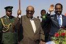 Sudan's President al-Bashir waves next to Somali President Mohamud during inauguration of Roseires Dam's height increase in Damazin