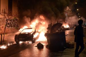 A man walks past a burning car in central Athens after …