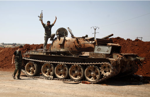 A Free Syria Army fighter waves from the top of a destroyed army tank in the town of Anadan on the outskirts of Aleppo, Syria, Monday, Aug. 6, 2012. (AP Photo)