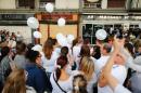 People hold white ballons as they gather in tribute to the victims in front of the "Au Cuba Libre" bar in Rouen, northwestern France, on August 11, 2016