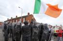 A Republicans holds an Irish Flag as he stands next to a line of police during clashes in the Oldpark area of north Belfast on August 9, 2015, after police stopped an annual anti-internment parade