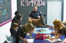 In this Feb. 18, 2013 photo provided by K9s4KIDS, Harris County Sheriff's Deputy John Palermo and his dog Rico meet with children at the TutorVille HUB in Houston. Schools have beefed up security, staged mock drills and added metal detectors, cameras and alarms to prevent violence. Some think teachers should be armed and the National Rifle Association wants armed police in every American school. Kristi Schiller thinks some special dogs might do the trick. She wants her charity, K9s4KIDS, to do for schools what it’s done for police departments in the U.S. - place scores of trained dogs among their ranks through the nonprofit set up in 2009. (AP Photo/K9s4KIDS, Josh Welch)