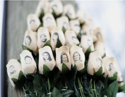 White roses with the faces of victims of the Sandy Hook Elementary School shooting are displayed on a telephone pole near the school on the one-month anniversary of the mass shooting that left 26 dead, including 20 children in Newtown, Conn., Monday, Jan. 14, 2013. (AP Photo/Jessica Hill)